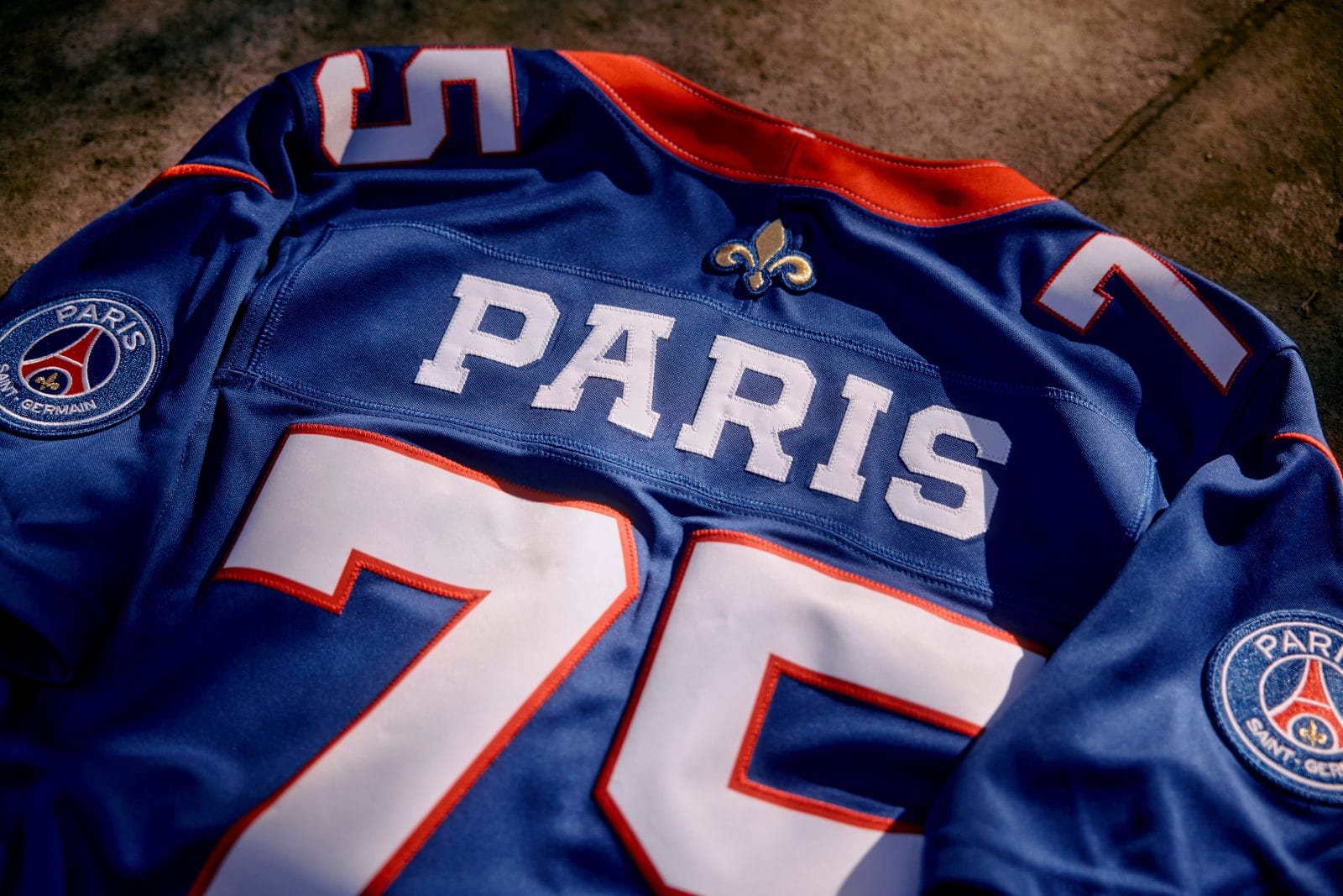 Close-up of the blue PSG x NFL Paris Red and Blue jersey with PARIS, the number 75, the fleur-de-lis and the PSG crest on the sleeve