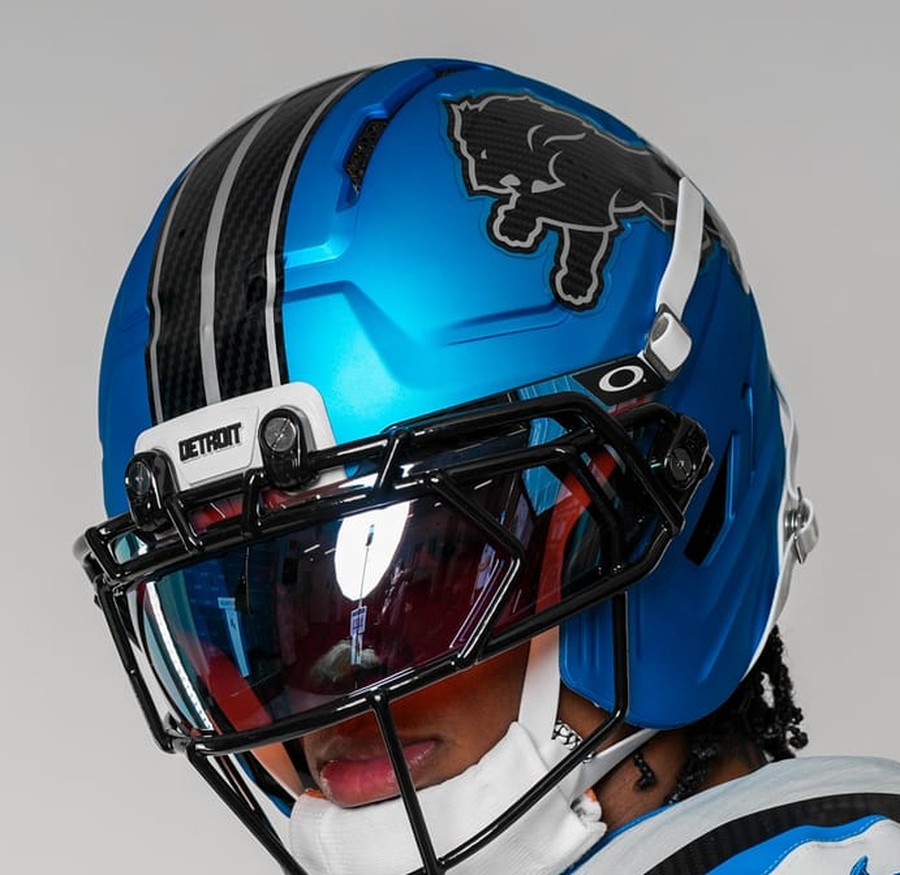 Detroit Lions Rivalries helmet, a metallic electric blue shell with glossy carbon-fiber racing stripes, a carbon-fiber lion logo, and a DETROIT front bumper