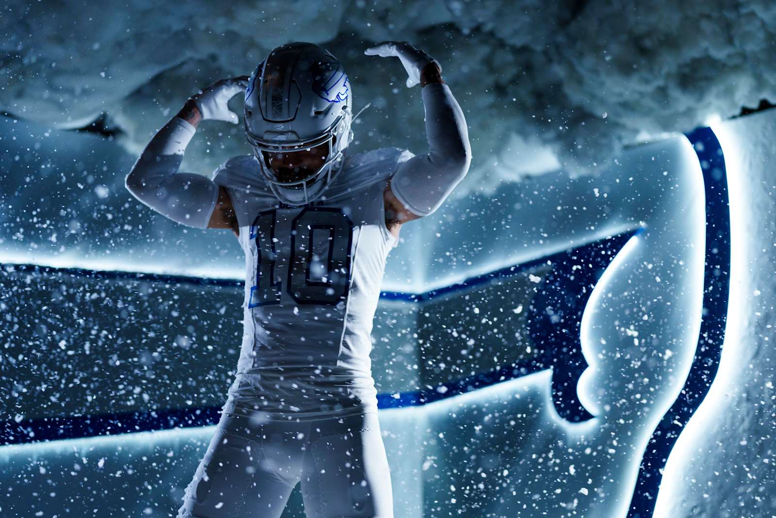 Buffalo Bills Cold Front Rivalries uniform, an all-white jersey and pants with silver and frost-blue numbers and cracked-ice shoulder texture, and a white metal-flake helmet with a cracked-ice center stripe and silver charging buffalo, shown in falling snow