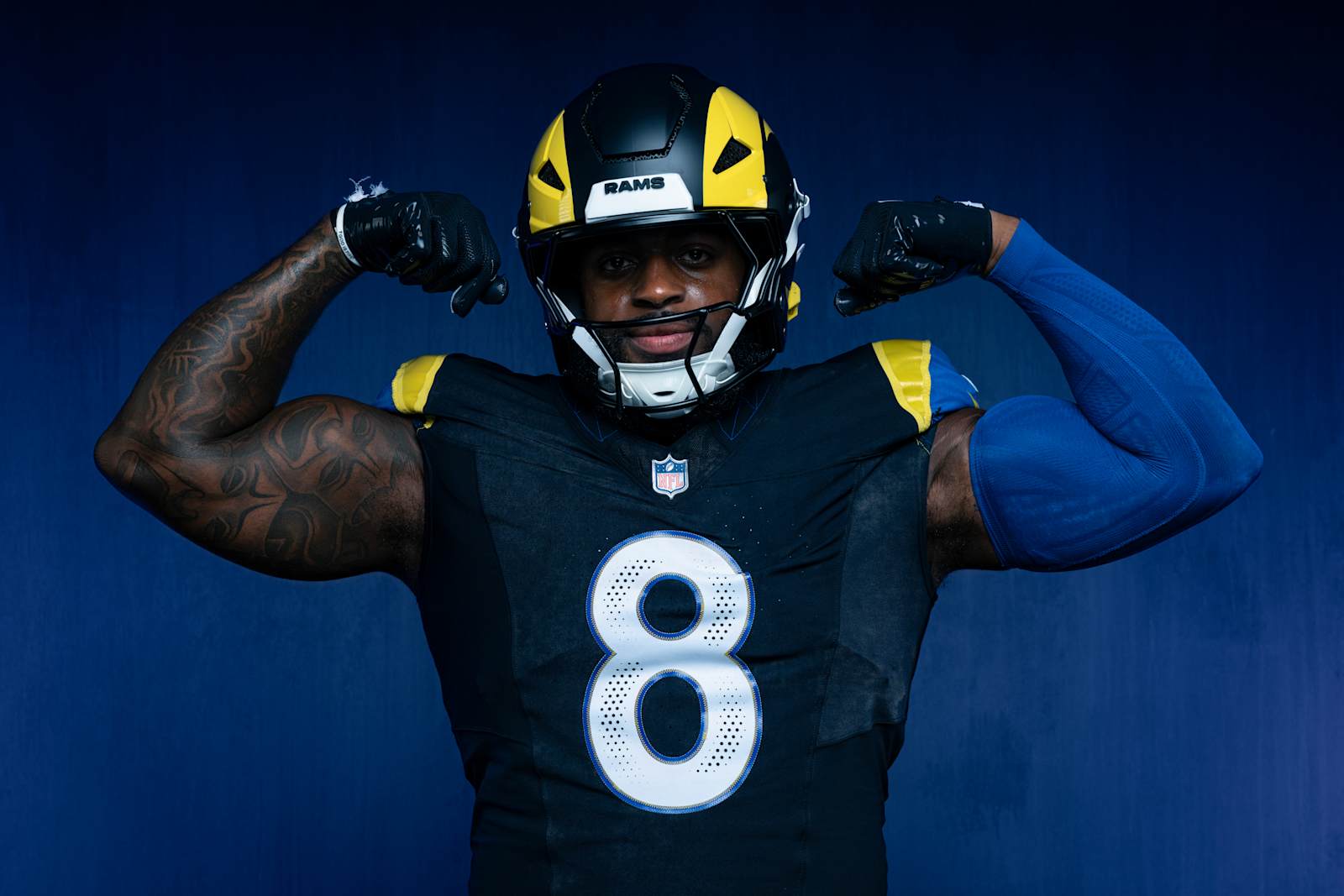 Los Angeles Rams Midnight Mode Rivalries uniform, a matte near-black jersey with white numbers outlined in blue, sol yellow and royal blue horn shoulders, and a black helmet with a yellow horn and RAMS bumper