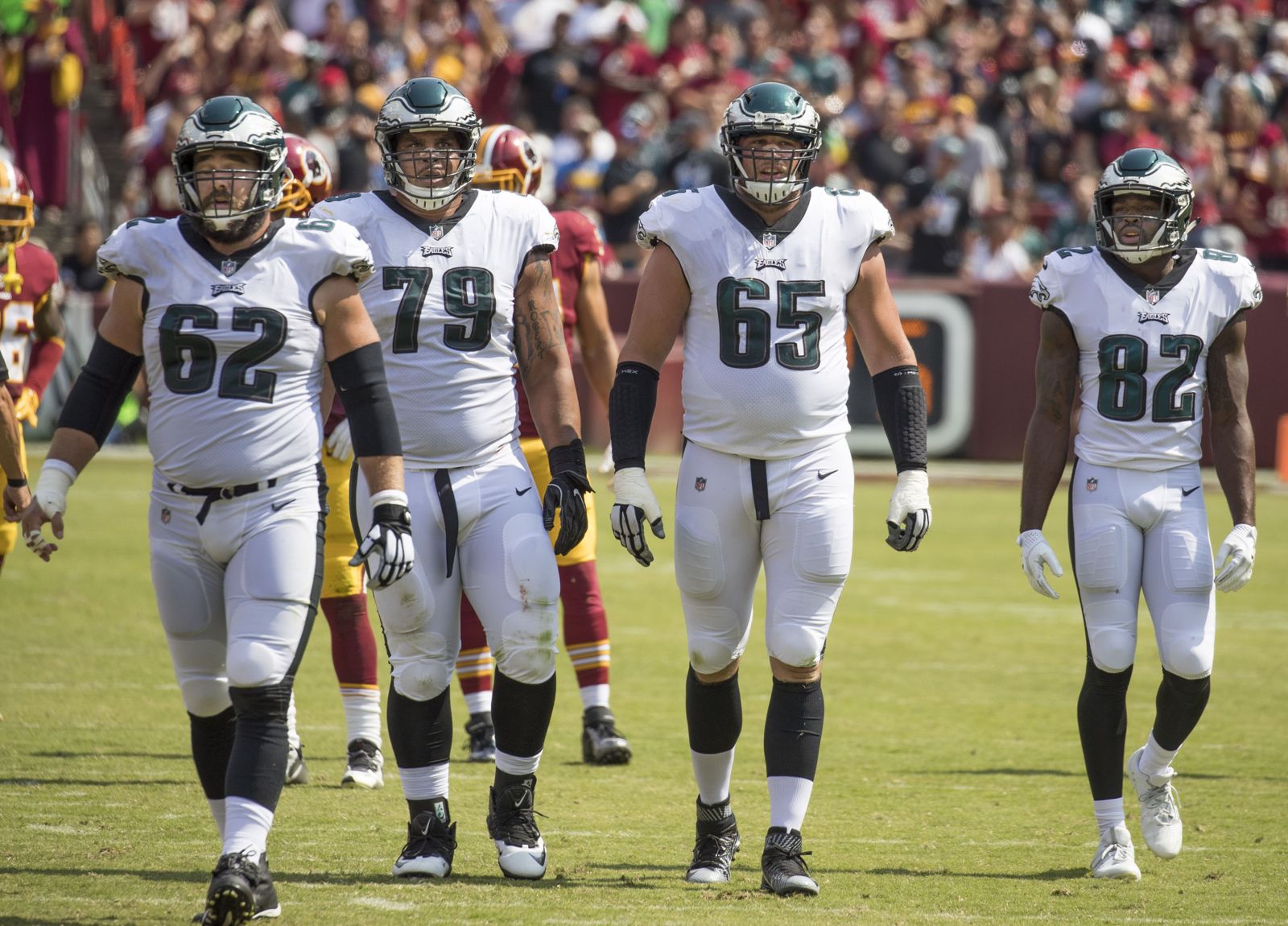 Eagles offensive linemen Jason Kelce, Brandon Brooks and Lane Johnson and receiver Torrey Smith in white road jerseys and midnight green helmets with silver wings, at Washington in 2017