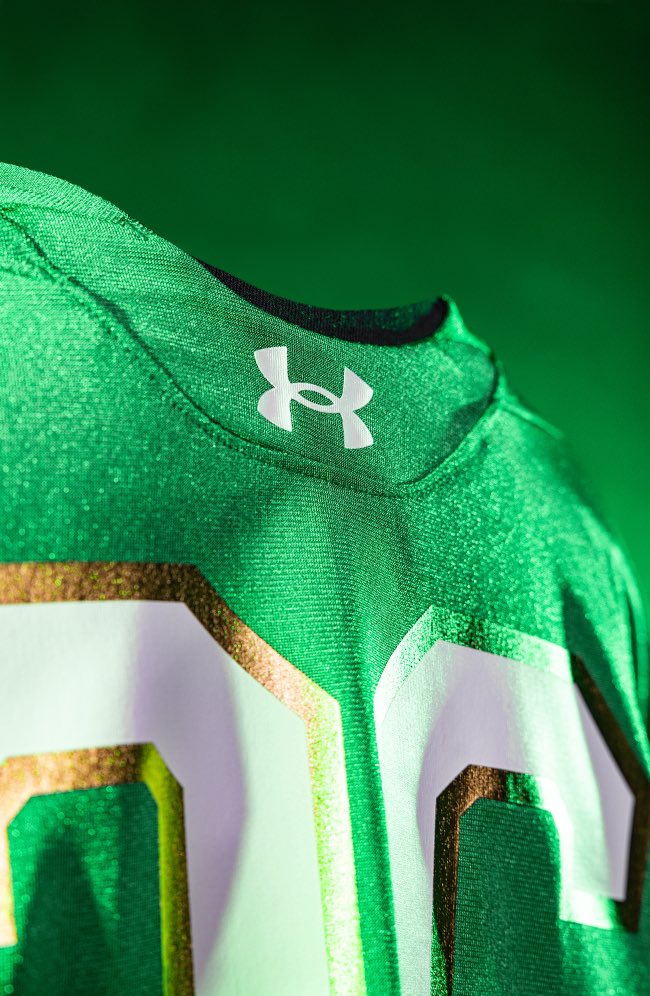 Close-up of the Under Armour logo and the gold-trimmed white numbers on the Notre Dame 2026 green jersey