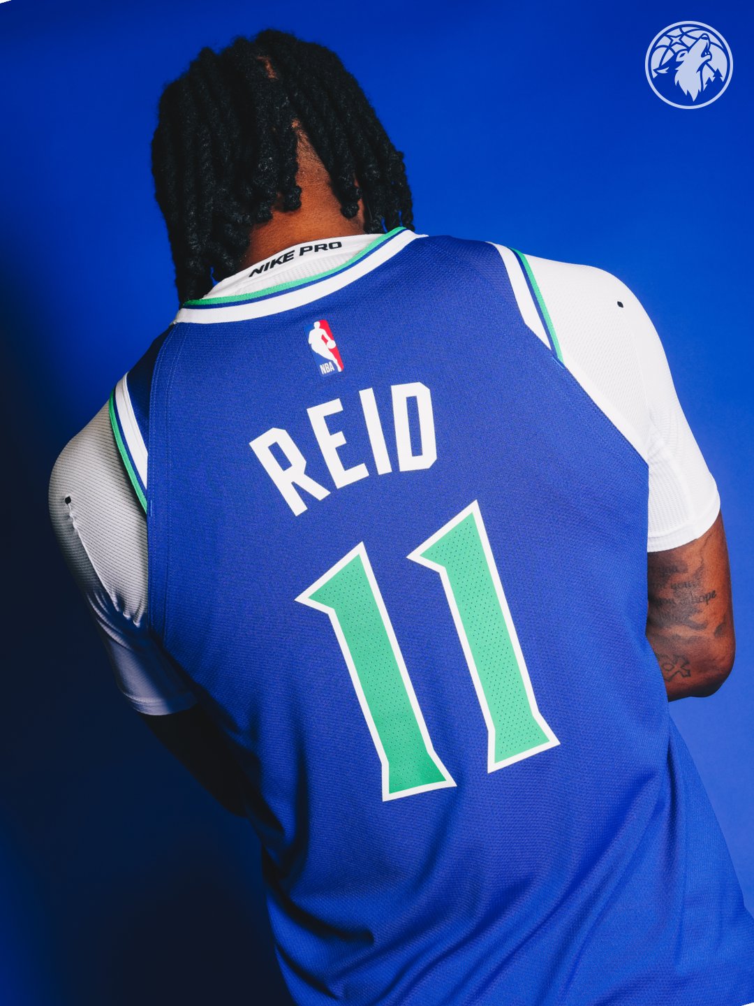 Minnesota Timberwolves new Icon Edition blue road jersey 2026-27 back view close-up of Naz Reid number eleven showing the white REID nameplate, the bright green number eleven, the saturated blue base of the jersey, and the white shoulder yoke trim with green and blue piping running across the collar