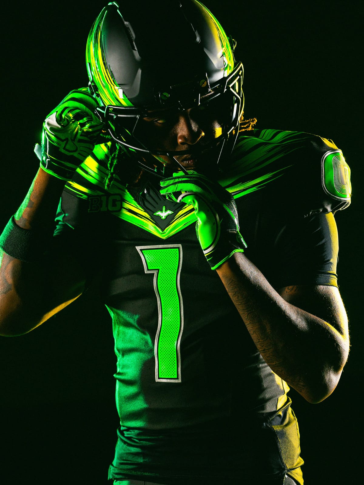Oregon Ducks Origin of Speed 2026 football uniform: Night Forest jersey with Green Strike and yellow speed-streak wings across the shoulders, green number 1 with silver outline, and a dark helmet with a green and yellow streaked wing
