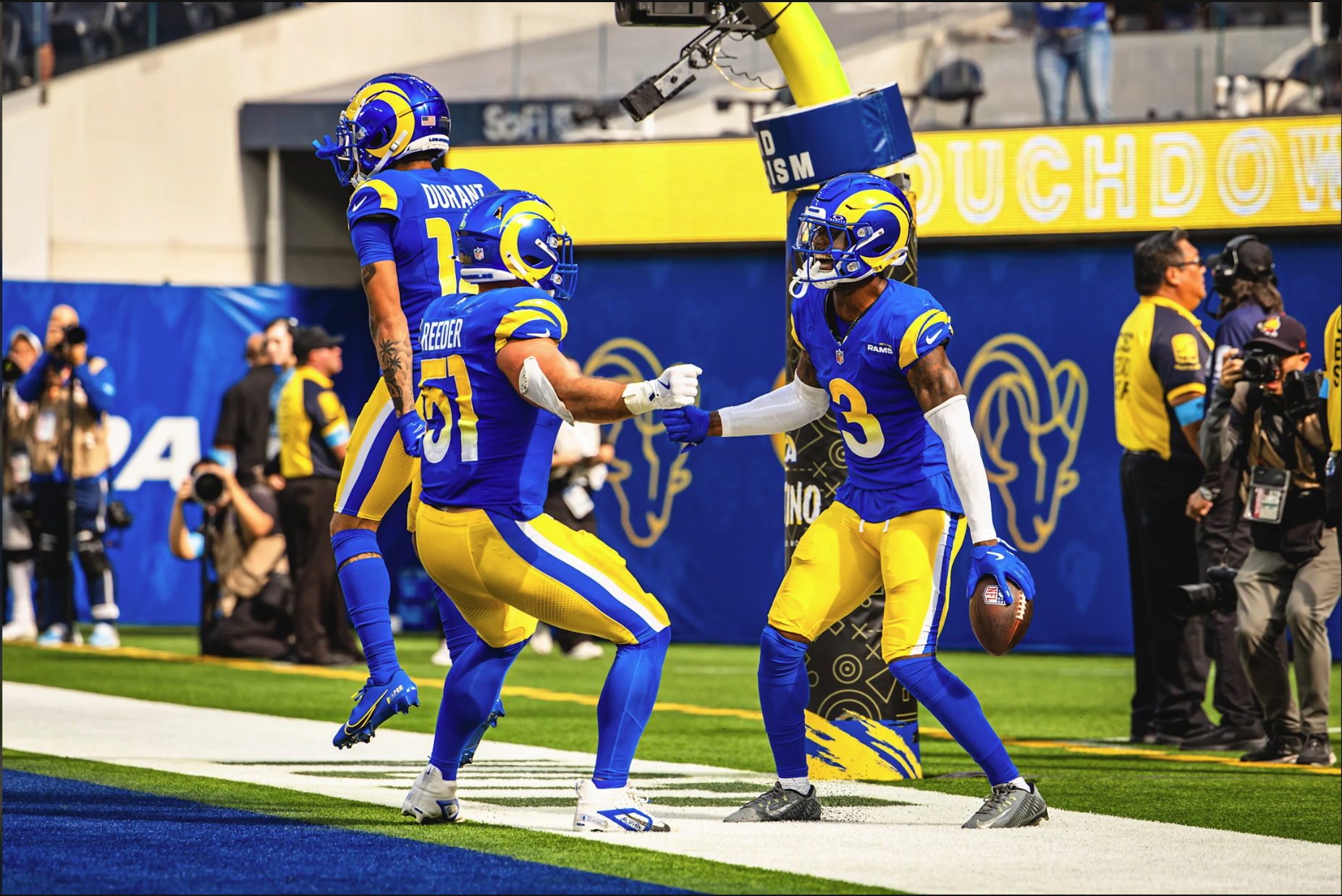 Los Angeles Rams players celebrating in the end zone in current blue home uniforms with gradient numbers