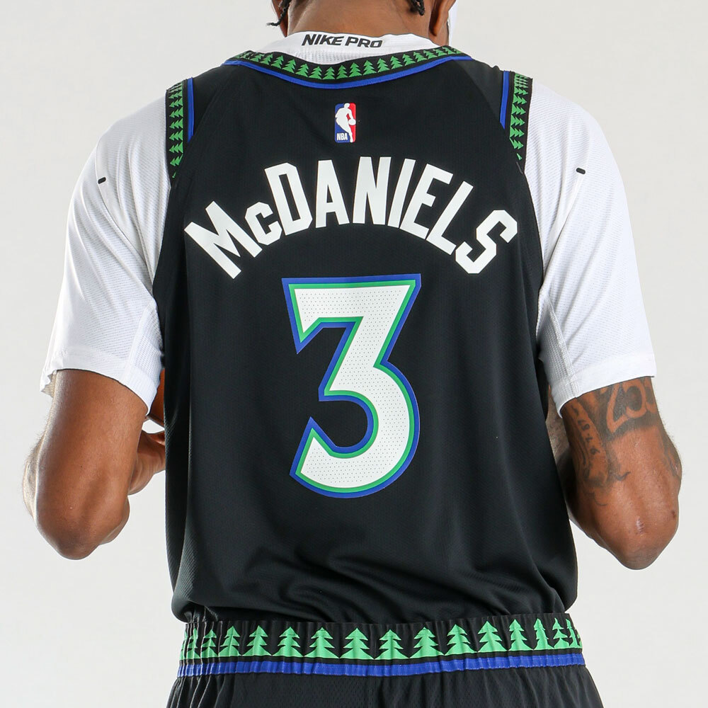 Minnesota Timberwolves new black alternate jersey 2026-27 back view with McDaniels nameplate in white, #3 number in white with green and blue outline, the tree print pattern running across the back yoke and the shorts waistband, the signature design element of the Wolves Hardwood Classic identity returning as the defining detail of the new black alternate
