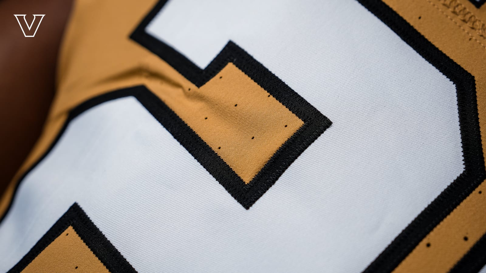Close-up of the white number with black outline on the Vanderbilt Commodores 2026 gold football jersey
