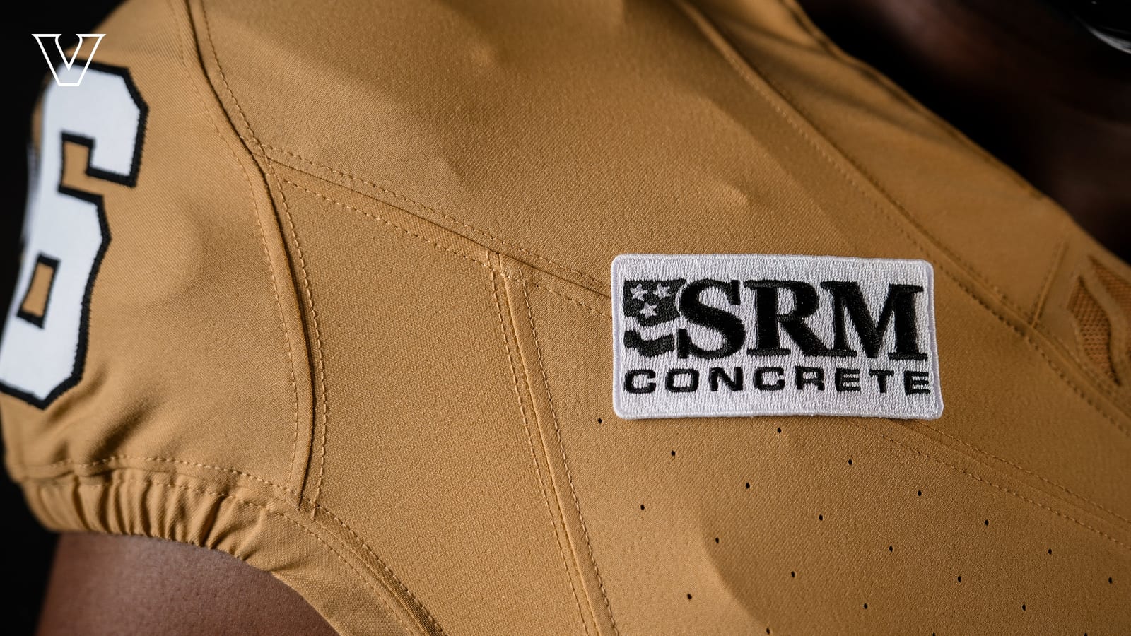 The SRM Concrete sponsor patch on the shoulder of the Vanderbilt Commodores 2026 gold football jersey, next to the white shoulder number