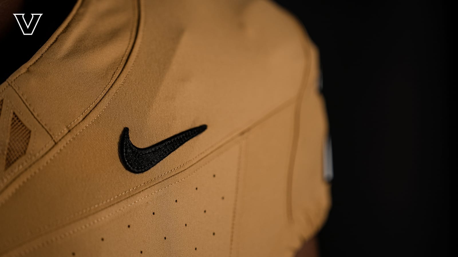 Detail of the shoulder and black Nike swoosh on the Vanderbilt Commodores 2026 old gold football jersey, showing the muted warm tone of the fabric